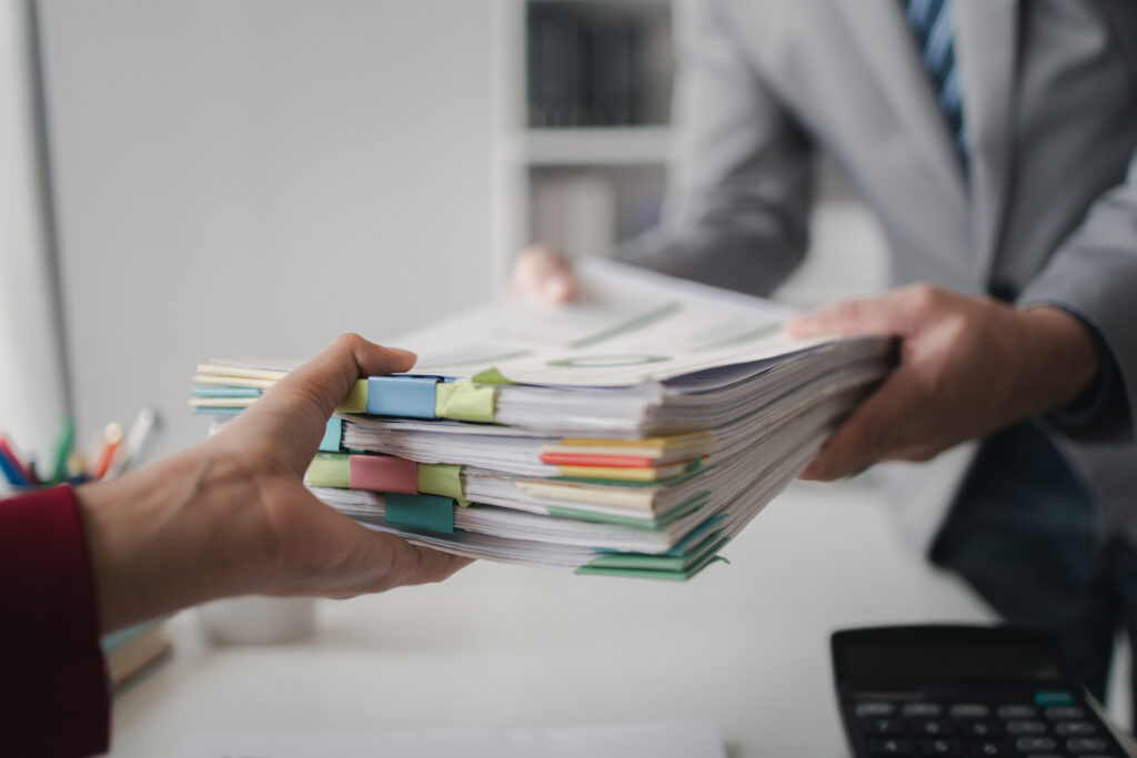 Two company employees handing over papers to each other.