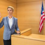 Mid,Adult,Woman,Raising,Hand,,Resting,On,Book,At,Witness
